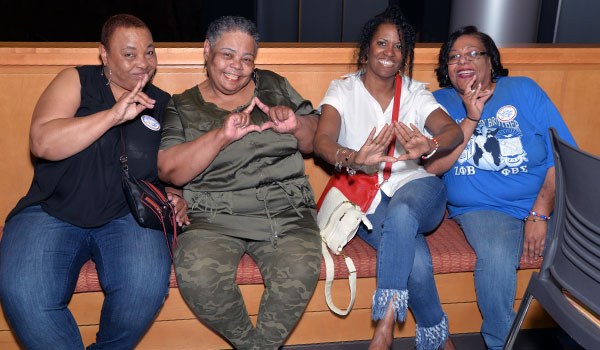 four women posing for photo on bench