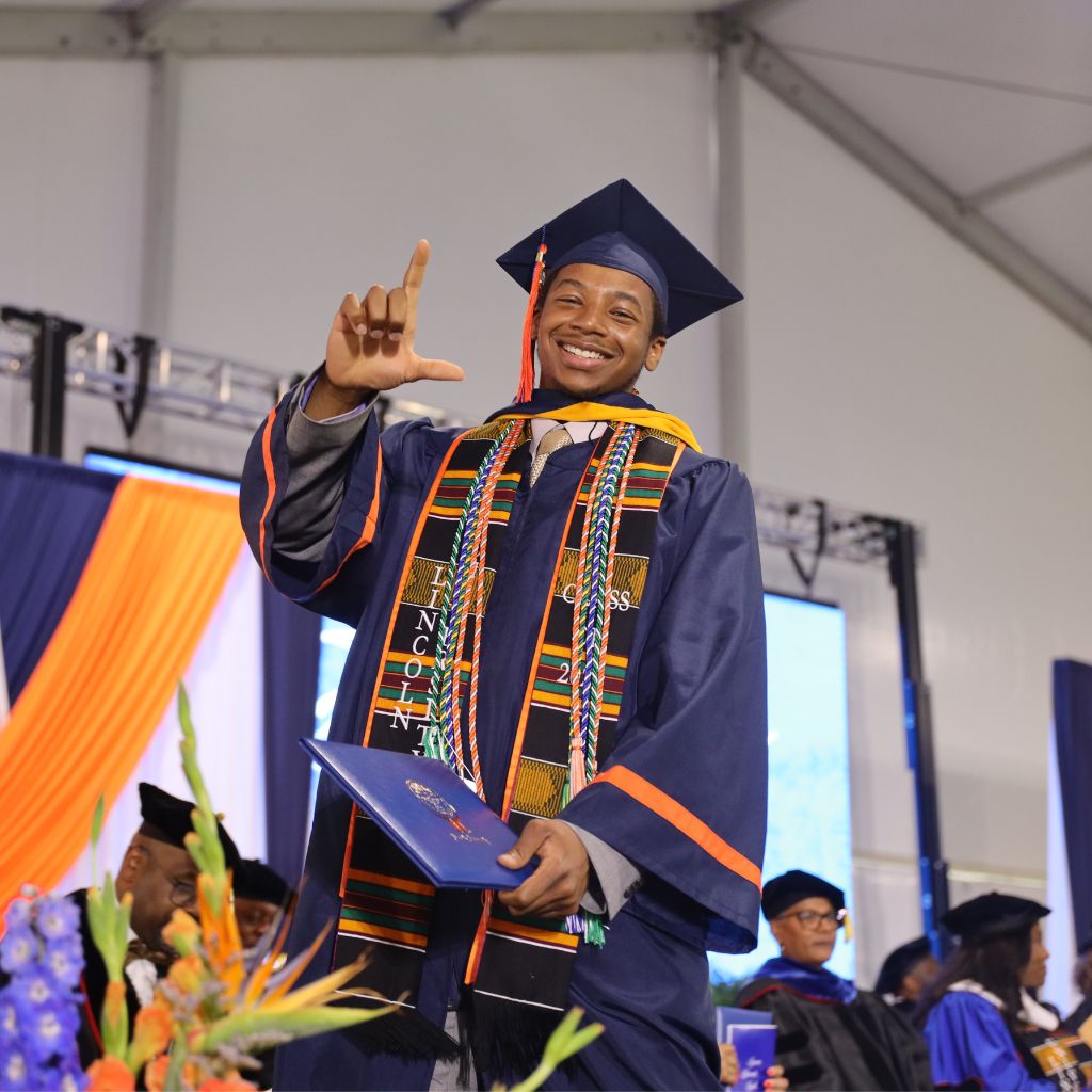 graduating student on stage throwing the L sign