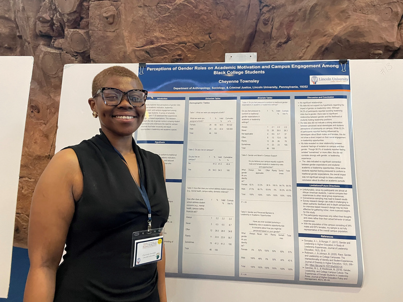 A female student smiling beside her poster
