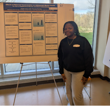 A female student smiling beside her poster